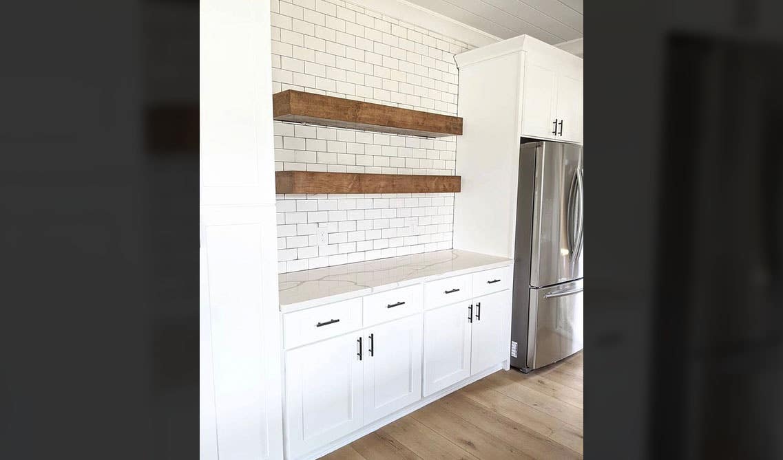 white cabinets with open wooden shelving, white subway tile backsplash and refrigerator 