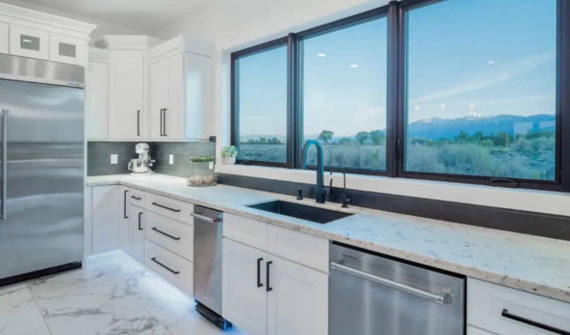 white kitchen with cabinets, countertop, black themed fixtures, stainless steel appliances, Large window 