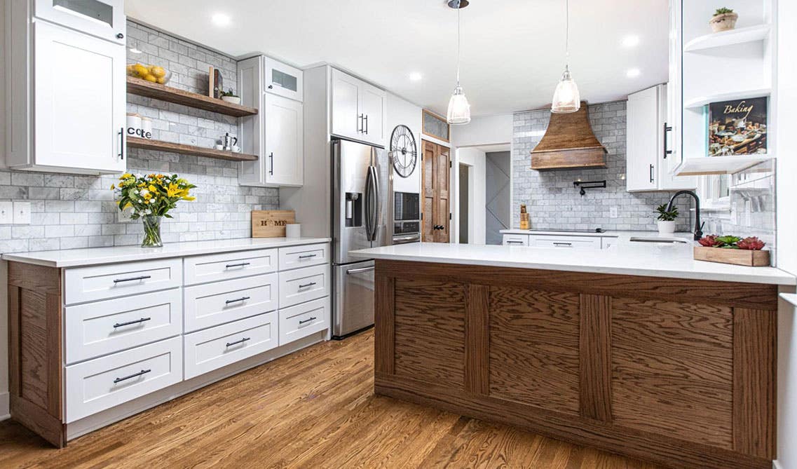 Stylish Kitchen with white cabinets, brick style backsplash, pendent lights above kitchen island, open shelves and spc flooring