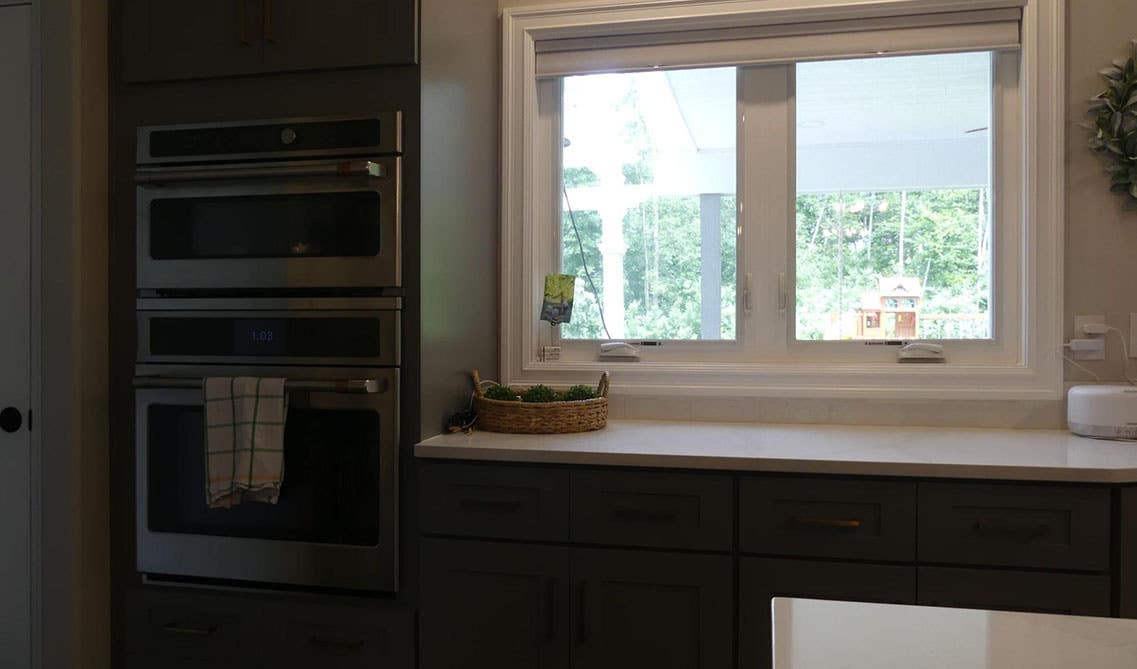 Kitchen window above gray cabinet and white countertop