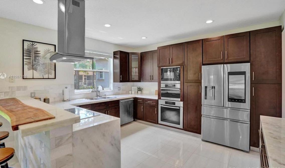 Modern kitchen design with wood cabinets, white countertop, stainless steel appliances and wall art