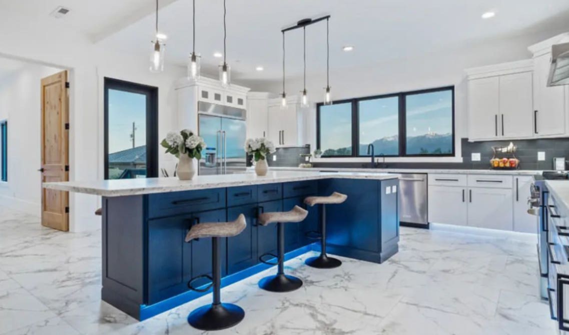 Modern kitchen with white cabinet and navy blue island, pendulum lights