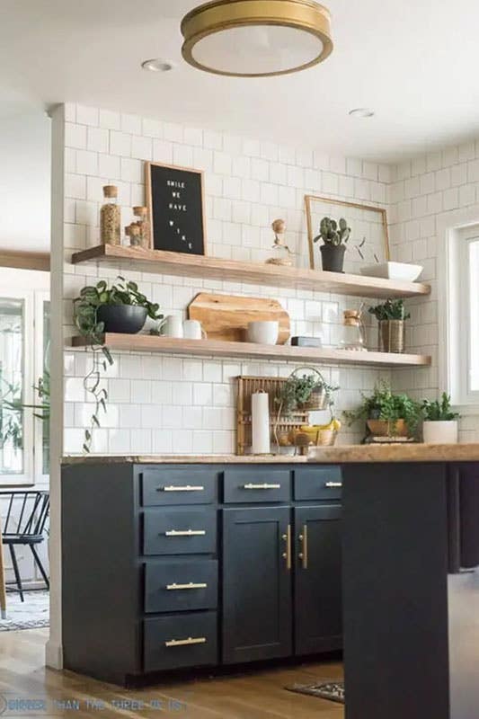 Kitchen design with dark base cabinets with gold hardware, open wooden shelving and wooden countertop