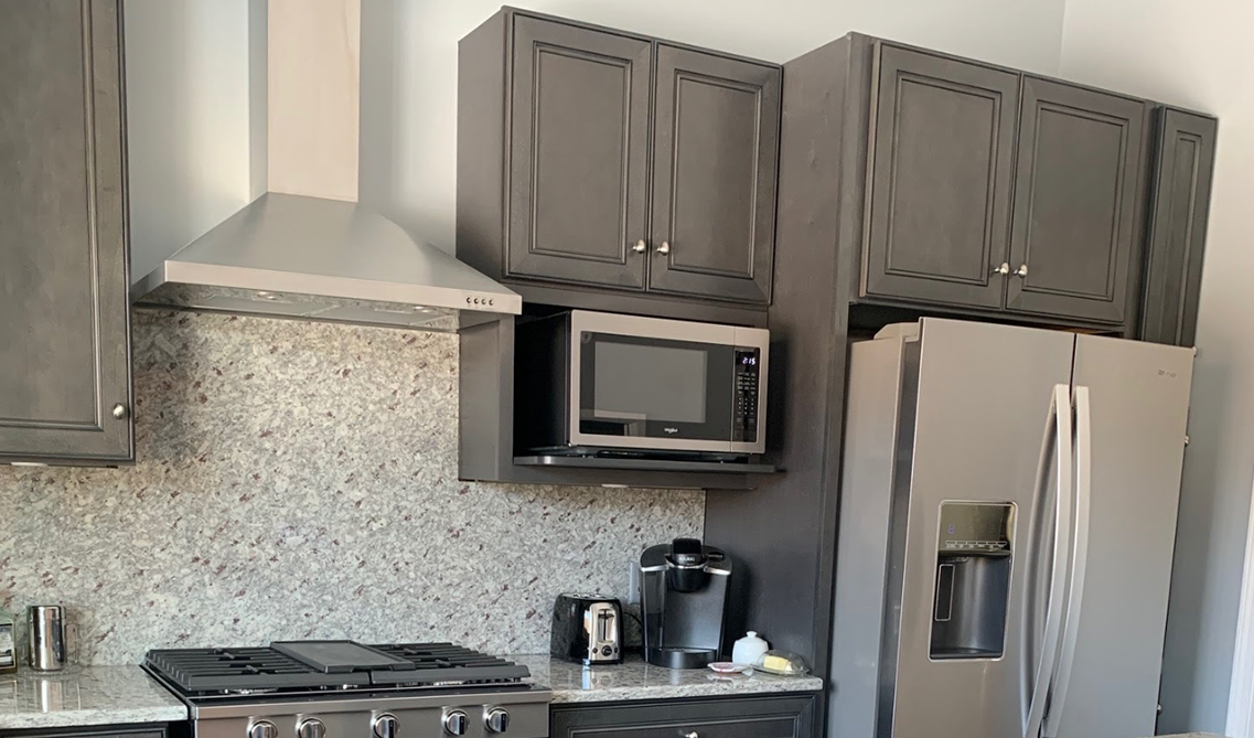 Driftwood gray kitchen cabinets paired with stainless steel appliances and granite backsplash matching countertop 
