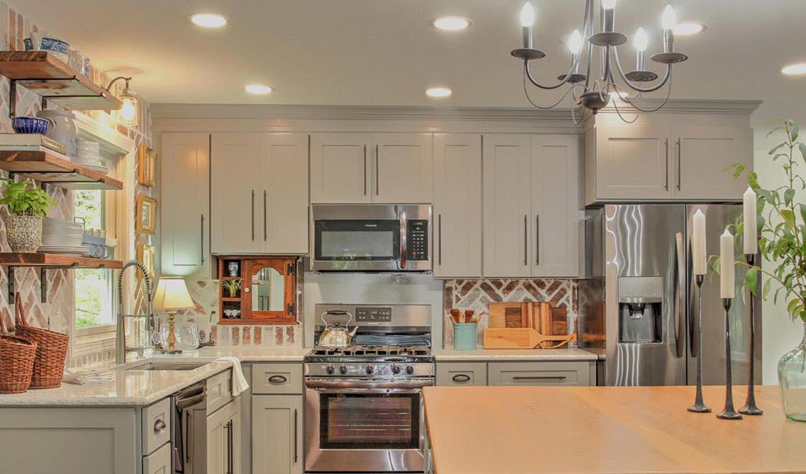 Kitchen with Grey Shaker Cabinets with black pulls, open shelvings, stainless steel appliances and white marble countertop