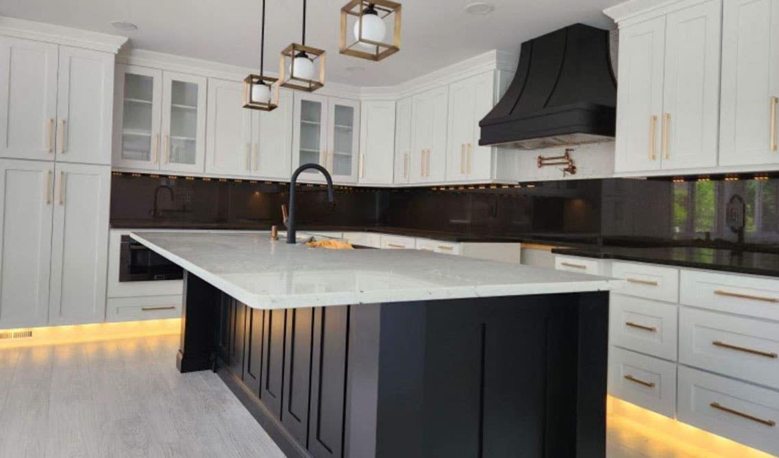 Kitchen design with white cabinets, black tile backsplash and statement lights