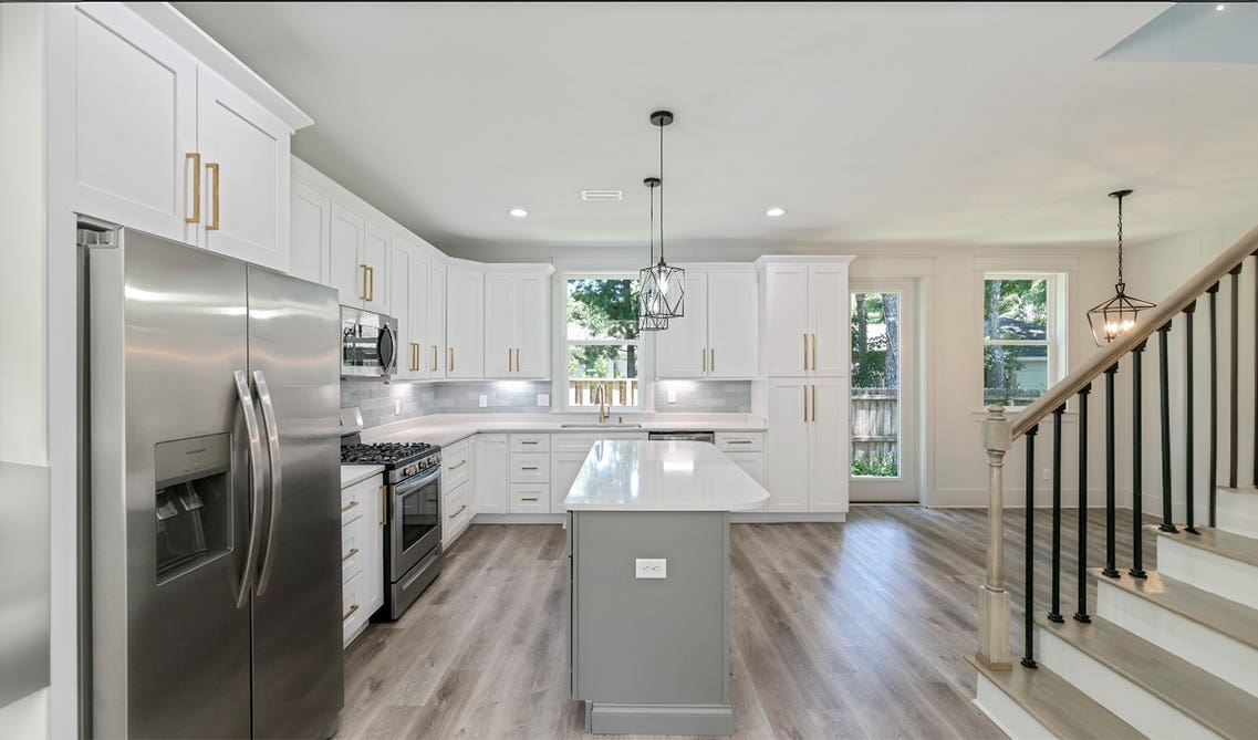 L shaped kitchen layout features white shaker cabinets and stainless steel appliances