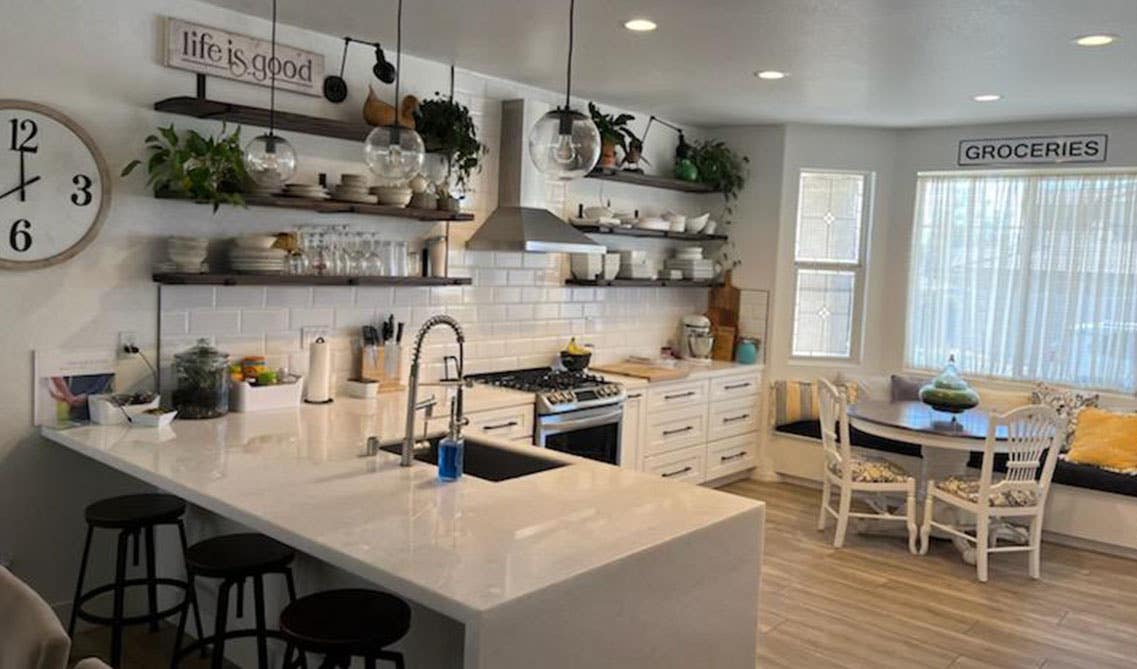 peninsula kitchen layout with white shaker cabinets and countertop, floating shelves, sitting area 