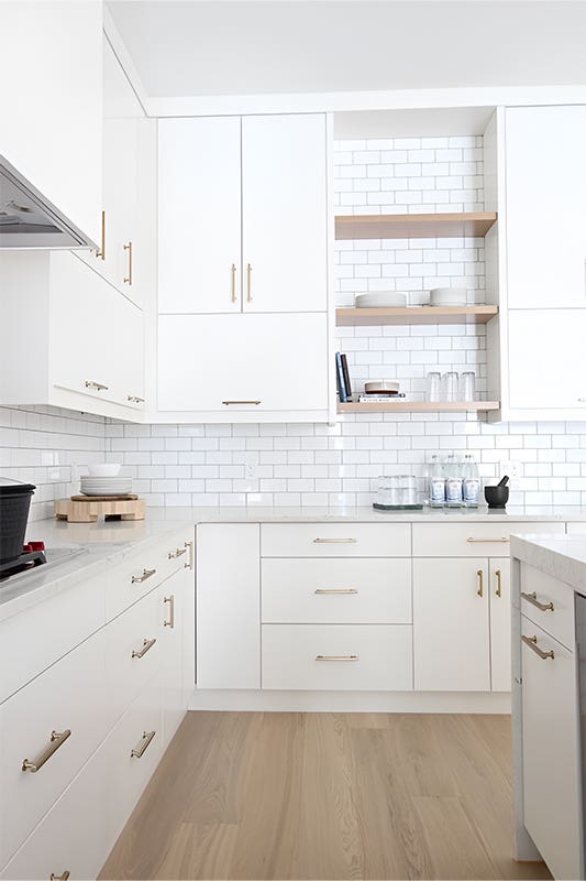 Laminate Cabinets paired with gold pulls and wood floating shelves 