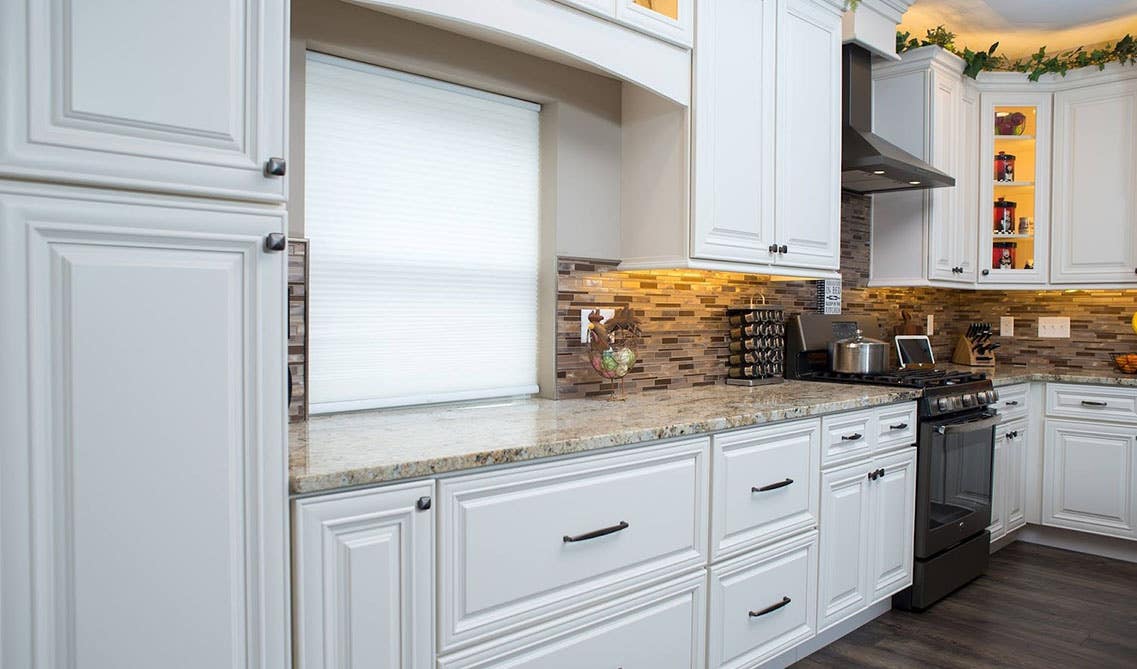 Antique white kitchen cabinets with marble countertop kitchen, showcasing charming decorations between the cabinet crown molding and ceiling