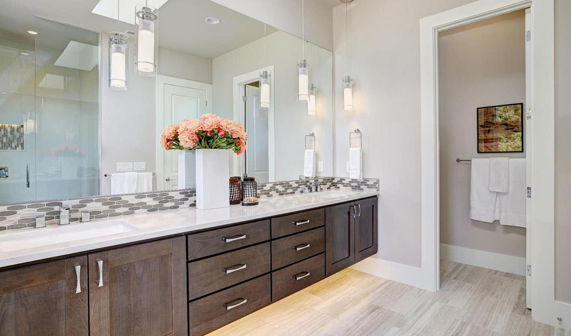 Bathroom design features wood storage cabinets with white countertops and large mirror