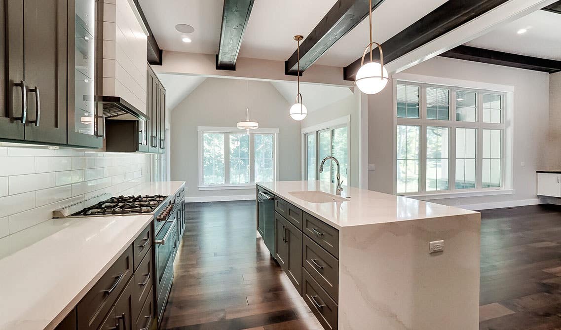 White and gray kitchen with large island, white countertop and Layer Lighting