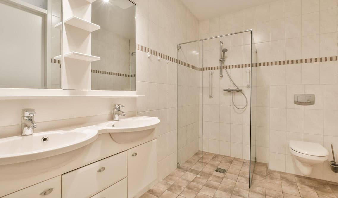 Bathroom design features wall mount vanity with sink, floating shelves with mirror and shower area