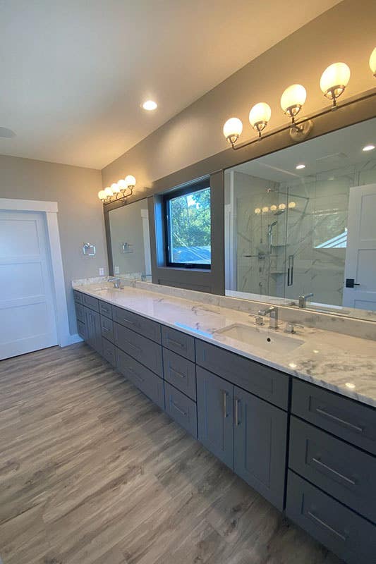 Bathroom with marble countertop, double sink and gray shaker cabinets