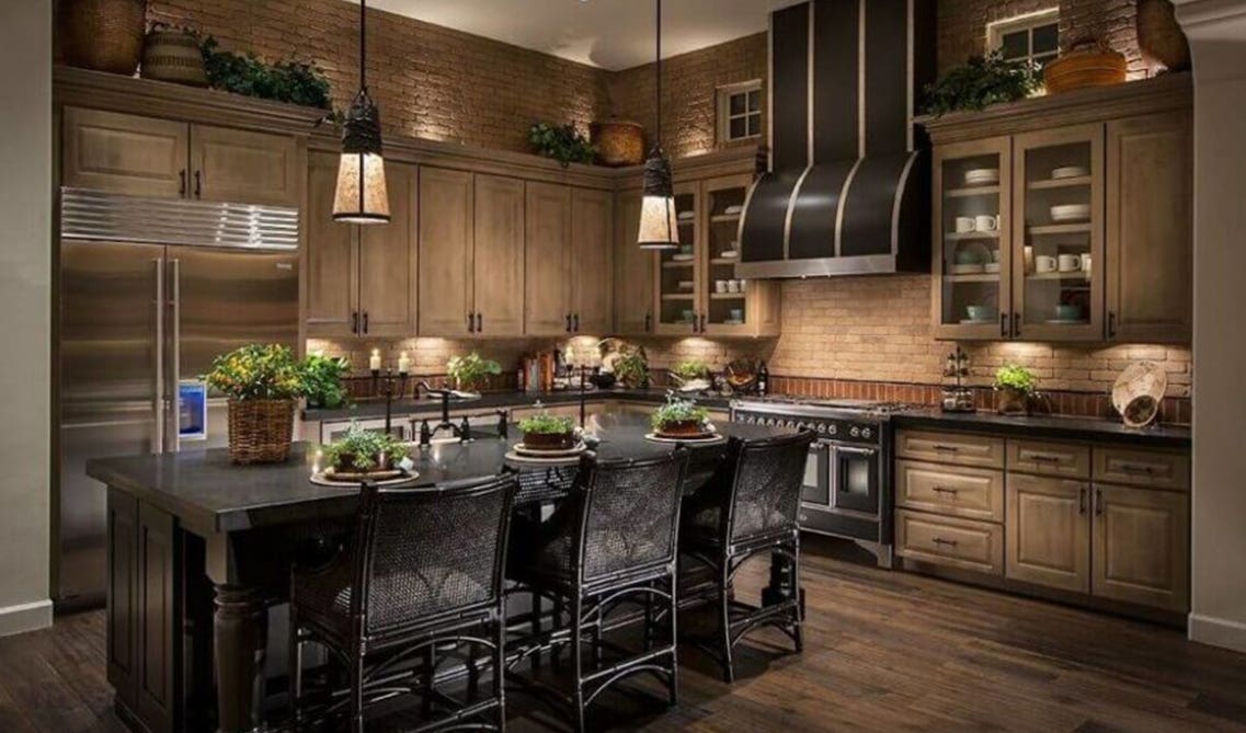 beige tone of cabinets with under-cabinet lighting and deep brown range hood, black kitchen island, and deep grey marble countertops