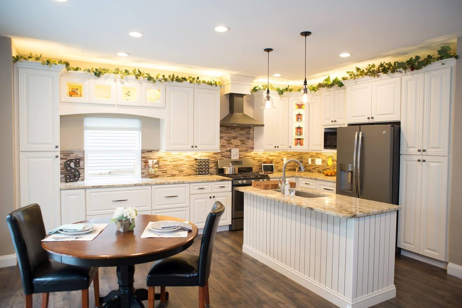 White kitchen with small island, marble countertop and beautiful pendant lights