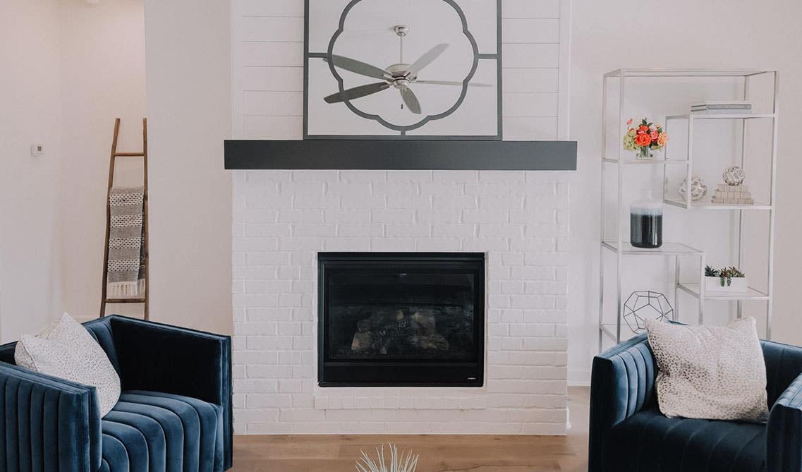 Warm seating area with mirror placed over electric fireplace and navy blue sofa and wooden flooring