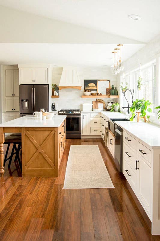 Modern farmhouse kitchen design with cream cabinets with matt black hardware, floating shelves and wooden flooring