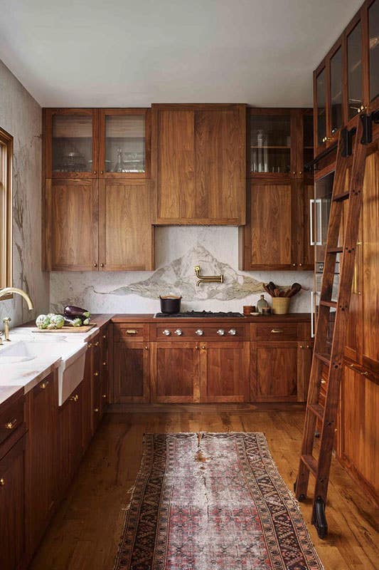 Modern rustic kitchen paired with natural tone cabinets, gold hardware, and marble countertop and backsplash 