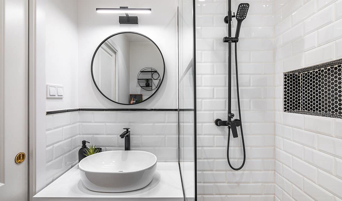 Modern bathroom with subway tiles, matt black fitting and fixture, round mirror and Ceramic basin