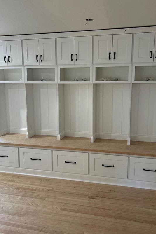 Mudroom space with white shaker storage cabinets and wooden flooring