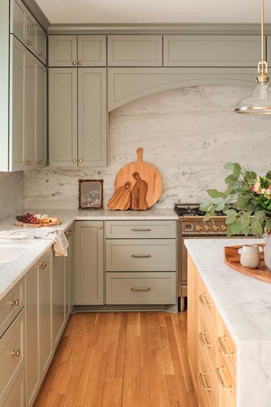 Muted Green Kitchen Cabinets with marble countertop, small island with waterfall countertop, and wooden floorings