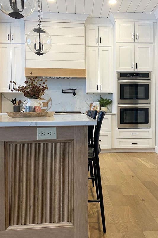 Small kitchen with white cabinets and black pulls, wood island and vinyl flooring