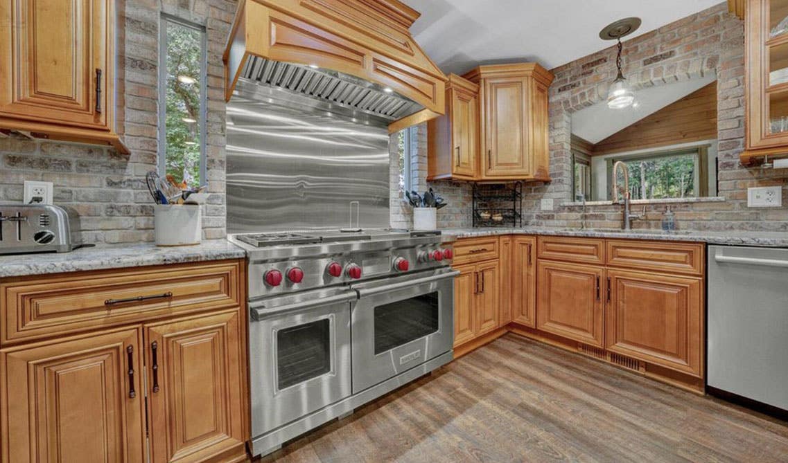 Natural wood kitchen cabinets with stainless steel appliances, marble countertop 