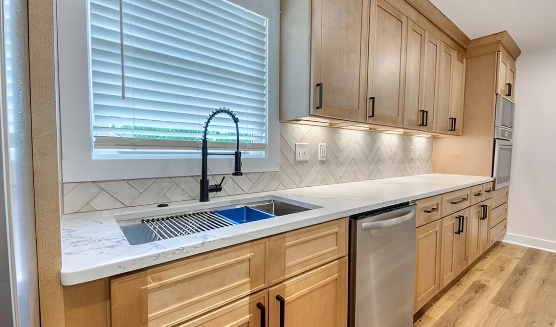 Natural shaker kitchen cabinets paired with matt black fitting and fixture, marble countertop and farmhouse sink