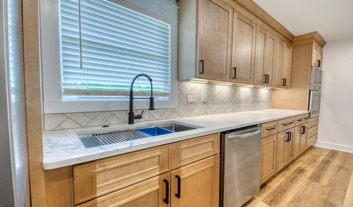 unfinished kitchen cabinets paired with marble countertop, stainless steel appliances, and under cabinet lights
