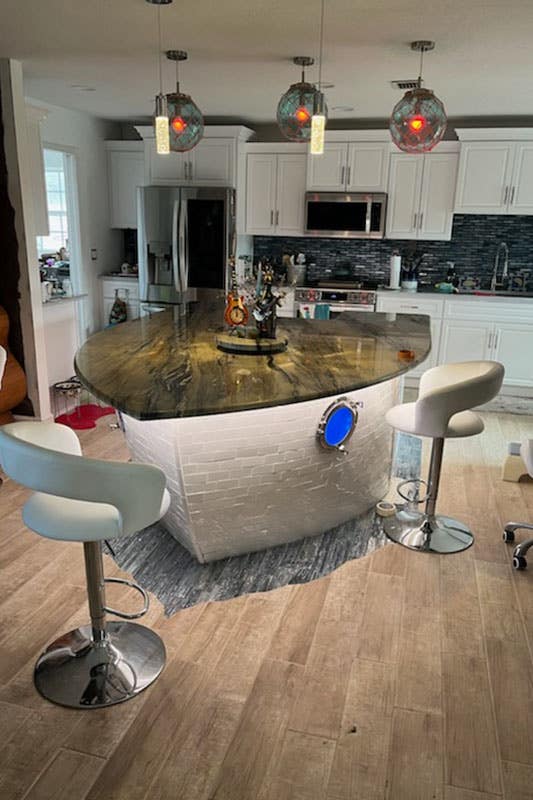 White cabinets kitchen with boat-shaped island and stone backsplash