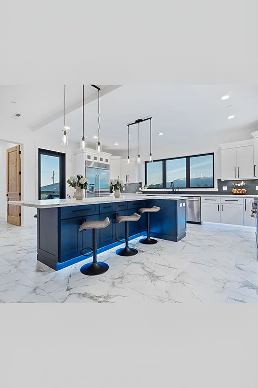 Navy blue shaker kitchen island paired with white countertop and stools for seating
