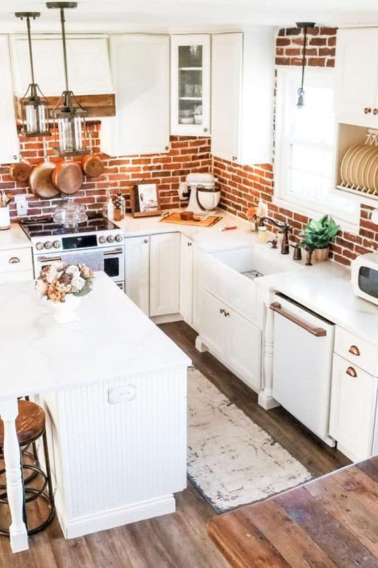 White kitchen with copper accents in light fixtures, and pots, and pans