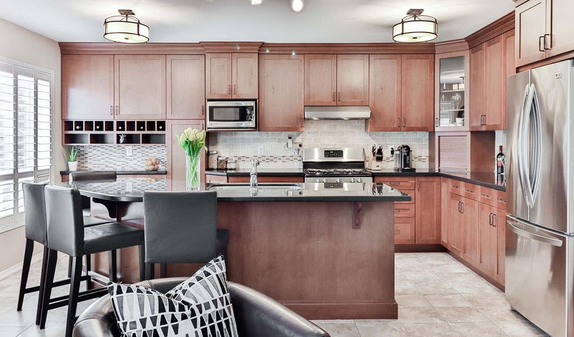 Oak cabinets Kitchen with large island, matte black hardware and black countertop, stainless steel appliances and beautiful ceiling lights