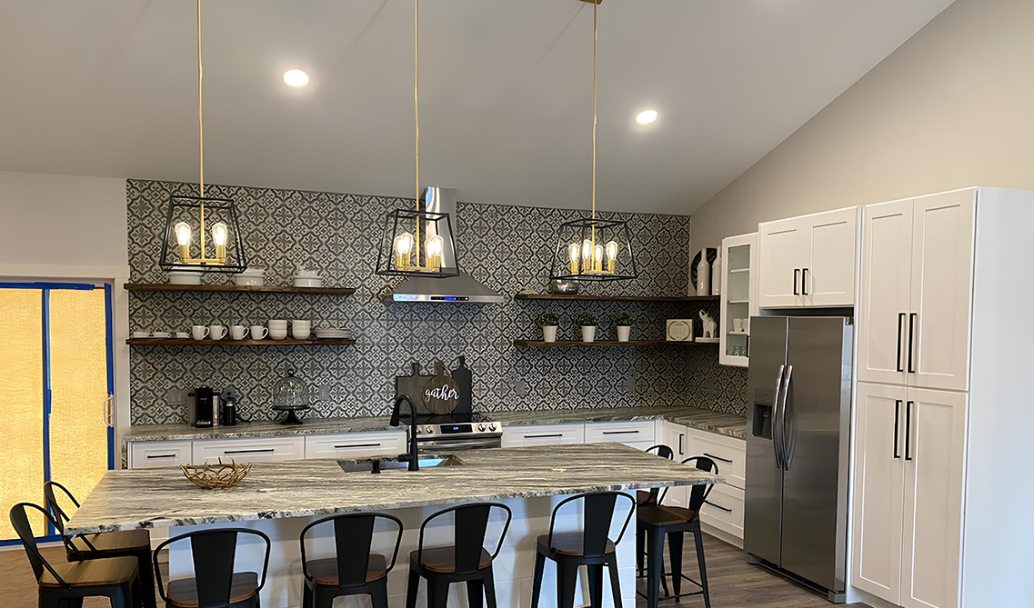 Wooden floating shelves paired with bold backsplash, white cabinets and stainless steel appliances