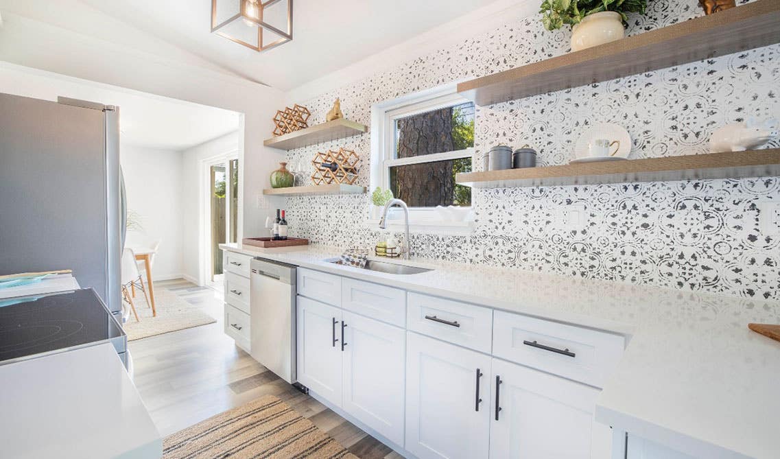 white cabinets with design backsplash, open shelving, and wooden flooring