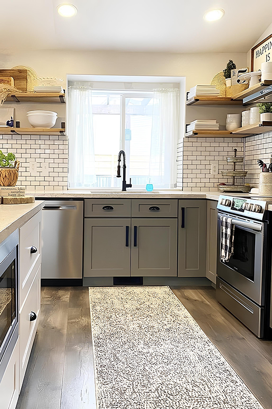 Wooden floating shelves paired with gray storage cabinets and white subway backsplash 