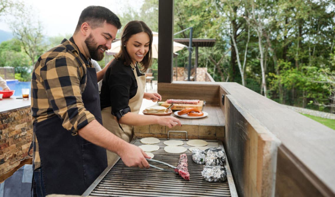 A man and women cooking in the outdoor kitchen 