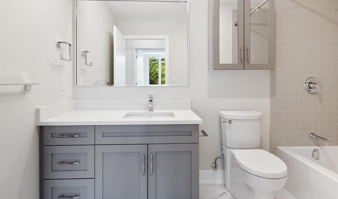 Small white bathroom with over the toilet cabinets