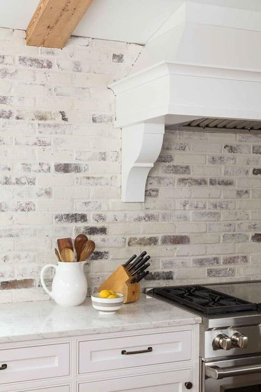 Painted Brick Backsplash with marble Countertop and bright white cabinets