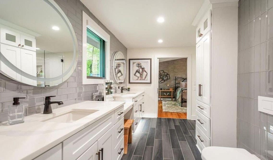 Modern white bathroom features shaker vanity with quartz countertops, subway wall tiles, matt black hardwares and dark SPC flooring