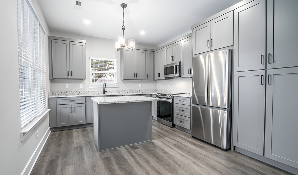 L shape kitchen design with gray cabinets and quartz countertop and stainless steel appliances 