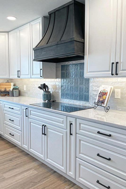 white cabinets with black hardware, white countertop, black wood hood, and SPC flooring 