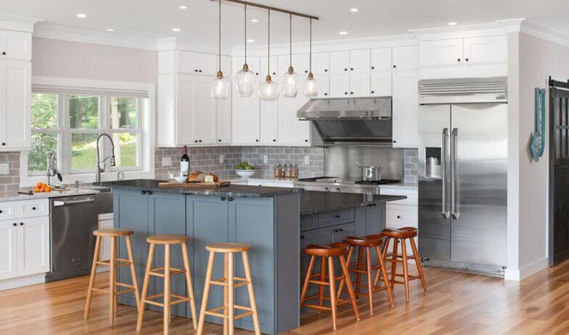 Modern kitchen design with cabinets and Island With Raised Bar, wooden chairs, pendent lighting, stainless steel appliances 