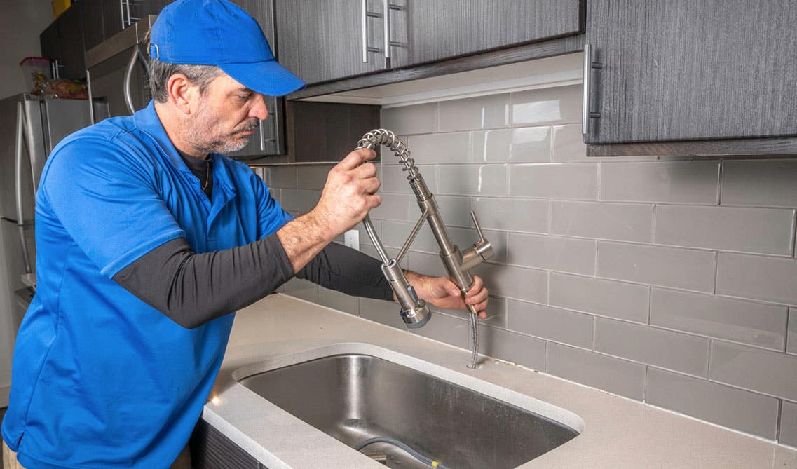 A Man with blue Tshirt changing old faucet 