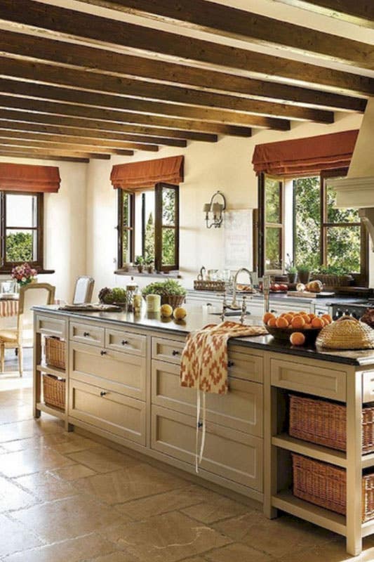 large european rustic kitchen with wood beams, beige cabinets, large center island and tile floors