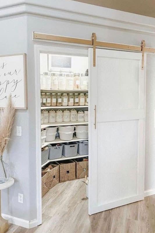 Rustic White Pantry with Barn Door stored with containers and baskets