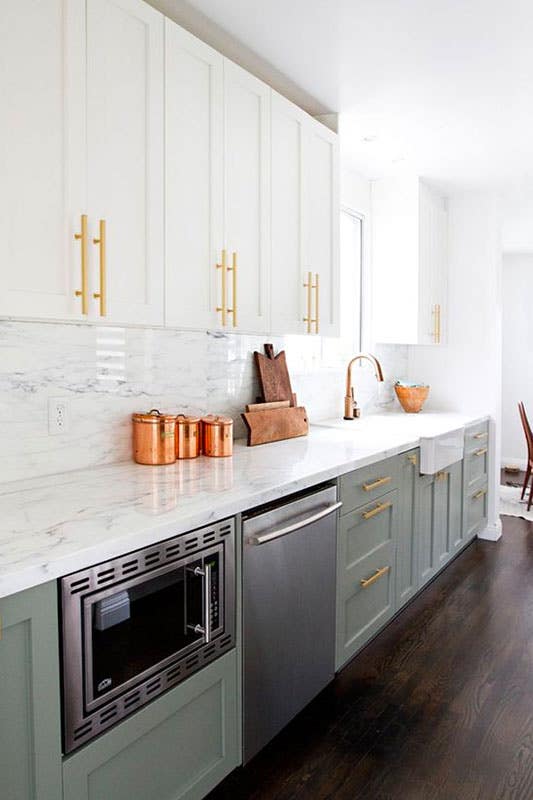 Sage Green and white kitchen cabinets with gold pulls, Marble backsplash and countertops 