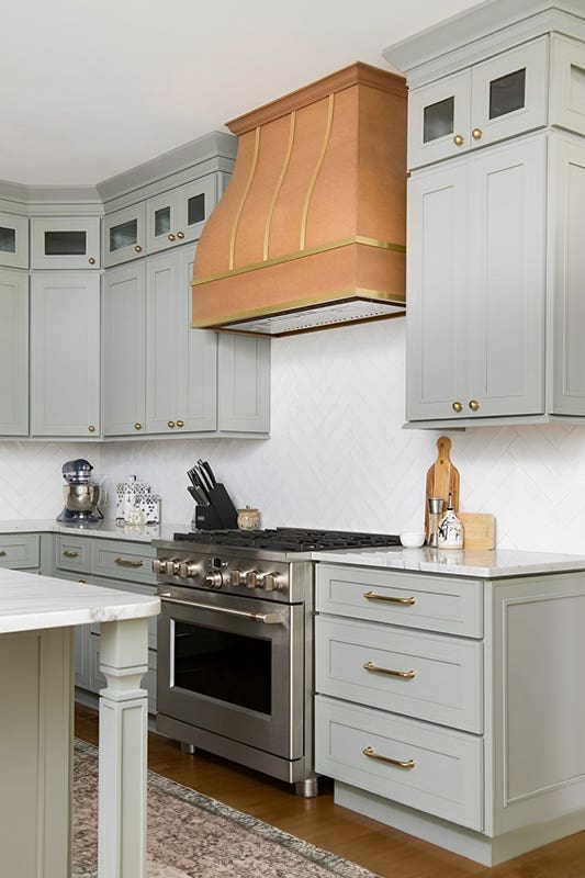 Sage green kitchen cabinets paired with gold hardware, marble countertop and stainless steel microwave 