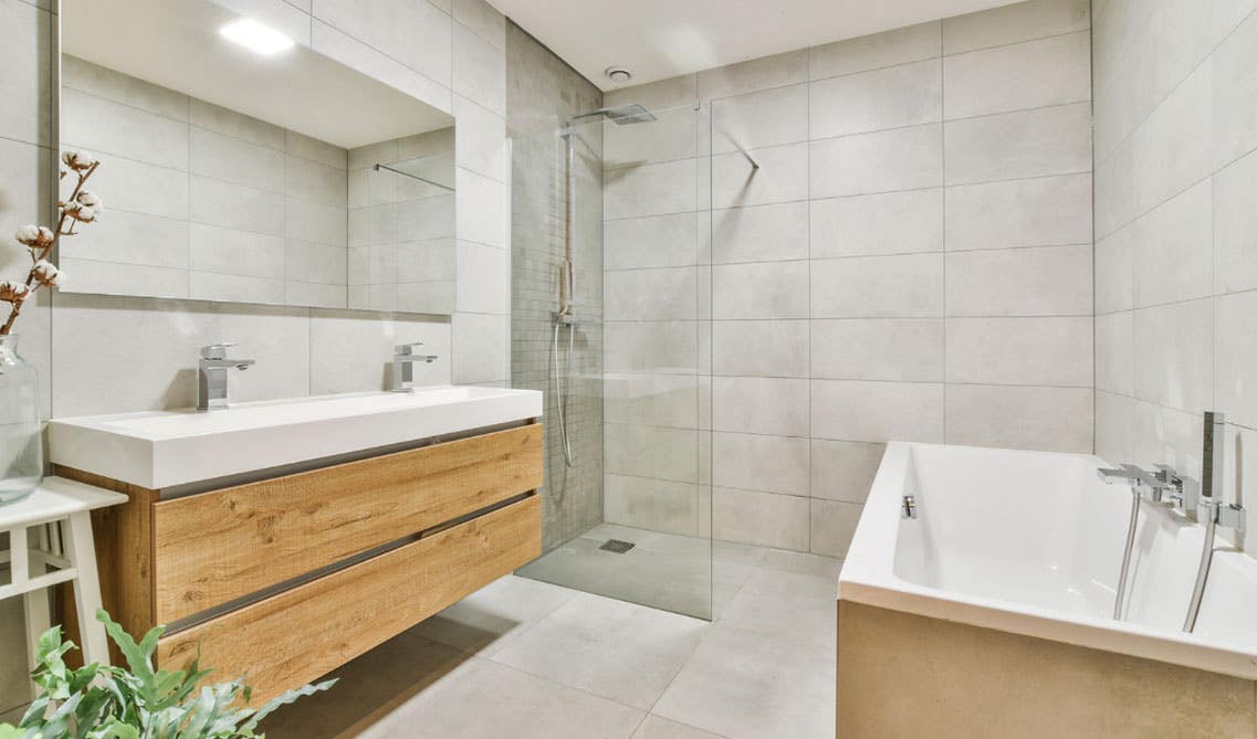 Scandinavian bathroom design features wood vanity, marble countertop, bathtub, and tile floor. 